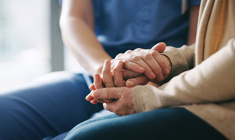 Closeup of senior and adult holding hands.